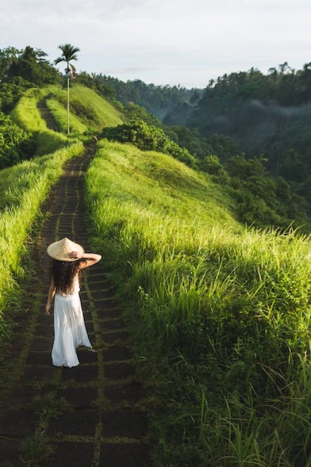 Woman walking on Campuhan Ridge way of artists, in Bali, Ubud. Beautiful calm sunny morning.